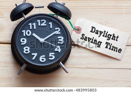 Daylight Saving Time words written on tag label with clock on wood background,Conceptual Royalty-Free Stock Photo #483995803