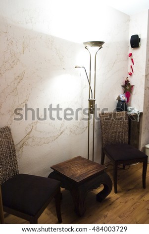 A picture of two chairs and a side table with a modern lamp in a stylish brown and white themed living room.