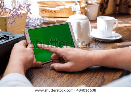 Tablet computer empty screen in man hands. Reading charts, document in cafe. Business man working out of office.