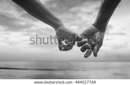 close up hand of senior couple hook each other's little finger together near seaside at the beach,black and white picture color,selective focus,love forever concept