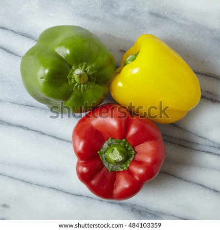 Three colorful sweet bell peppers on a marble counter top background