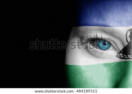 A young female with the flag of Lesotho painted on her face on her way to a sporting event to show her support.