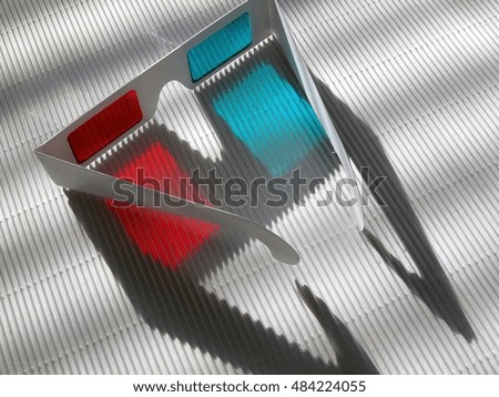 Stereo glasses made of paper and colored (red, cyan) film on relief white surface with nice shadows, back view