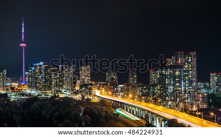 Glowing cityscape and buildings as light streaks along the Gardiner Expressway on a hot & muggy summer night in Lakeside Toronto, Canada.