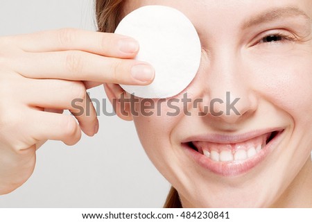 A picture of a happy woman cleaning her face with cotton pads over white background. Beautiful Face of Young Woman with Clean Fresh Skin close up. Beauty Portrait. Youth and Skin Care Concept