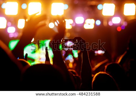 People makes photo with His smartphone on rock concert to share the moment with friends on social networks