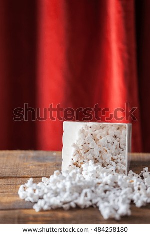 Popcorn In Classic Cinema Serving Box On Wood Background With Red Theater Curtains.