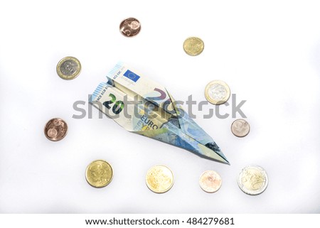 20 euro banknote folded into an airplane shape surrounded by euro or euro zone coins. money flying. how money travels european money