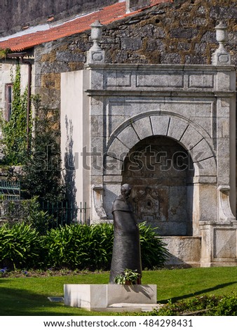 metal statue in the middle of garden with stone altar on the background