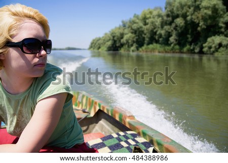 Young woman cruising in a boat on Danube river, looking to side 