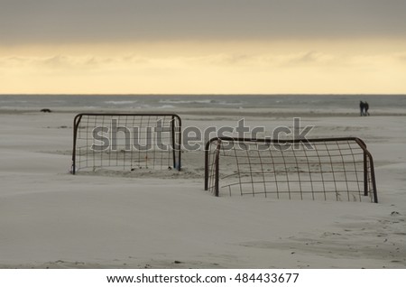 Two old rusted soccer goals on a beach at sunset
