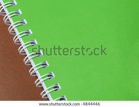 A green cover of a spiral notebook on a leather background