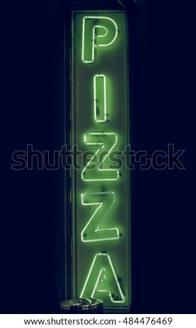 Vintage looking Green neon light pizza sign marking a pizzeria restaurant