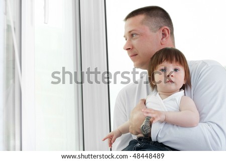 young father and her little beautiful daughter sitting at the window