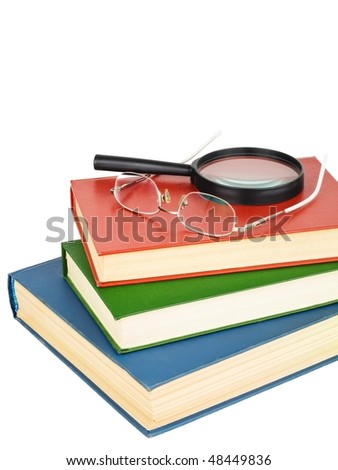 Glasses and magnifying glass on a pile of books, isolated on white background