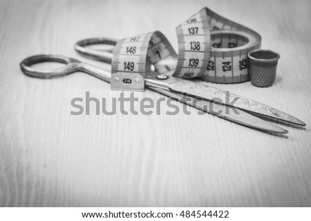 sartorial meter and scissors on the old wooden background  . Black and white photography.