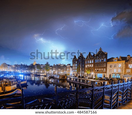 Fantastic collage. Beautiful lightning. Night in Amsterdam. Highlighting buildings and boats near the water in the channel. Art photography.
