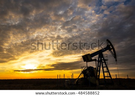 Operating oil and gas well, in remote field, under warm evening light Royalty-Free Stock Photo #484588852