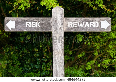 Wooden signpost with two opposite arrows over green leaves background. RISK versus REWARD directional signs, Choice concept image