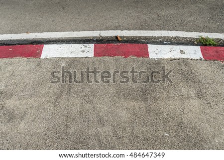 Concrete sidewalk with red and white curb