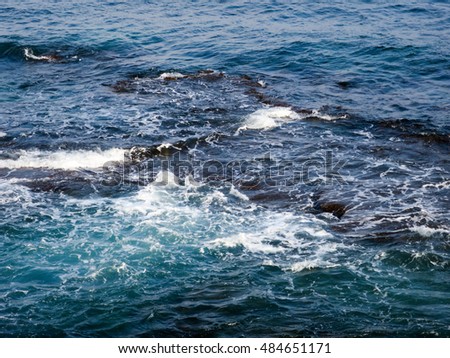 Water flowing around some rocks in the sea.