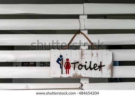 Wooden toilet label on white wooden wall