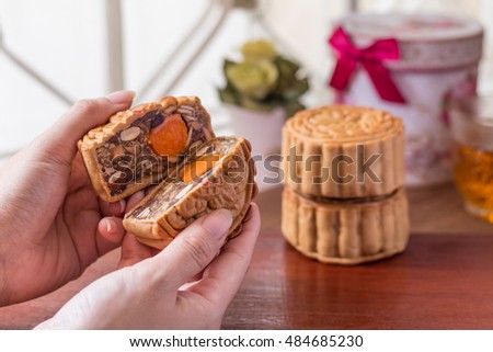 Mid-Autumn festival moon cake in woman hands with wooden background. Horizontal image