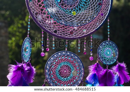 photo of a dreamcatcher made by hand, with using threads, beads and feathers rooster
