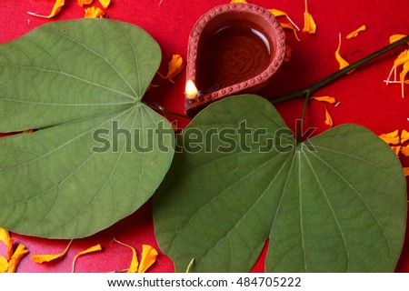 Indian Festival Dussehra, showing golden leaf and flowers with traditional diya on green background. Greeting card.
