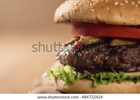 closeup fresh homemade burger with marble beef, cheese and vegetables on olive board
