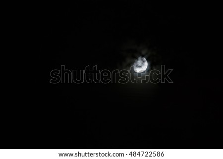 moon in a misty sky with branches on foreground