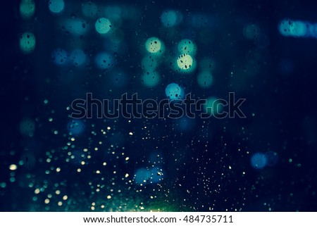 Abstract circular bokeh background. Rain drops on window with road light bokeh, City life in night in rainy season abstract background.