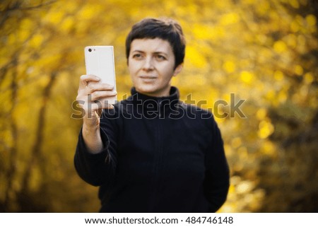 Woman taking selfies and having fun outside in the autumn forest