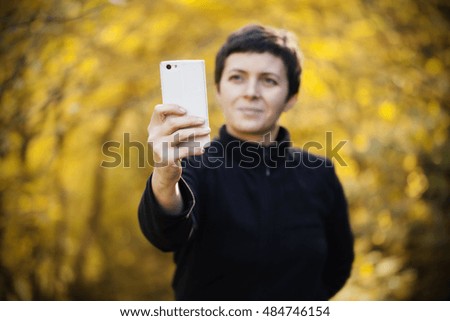 Woman taking selfies and having fun outside in the autumn forest