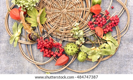 Beautiful Holiday autumn round composition of  fruits,berries, leaves,dried flowers and jewelry on wickerwork texture on coarse textured fabric.Celebration,New Year, Christmas,Rustic,Nature,Forest