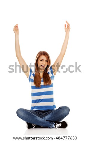Happy teenage woman sitting with arms up