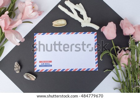 Flat lay composition with shells, coral, envelope and flowers. On envelope - inscription Air Mail in English, French and Spanish. Photo background. Top view with white and black paper. Nautical decor