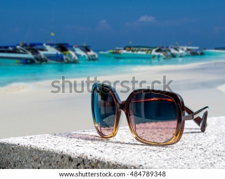 Sun glasses over the beach with blue sky blurred background / summer travel, recreation & lifestyle conceptual