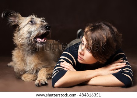 Portrait of a beautiful young woman with a funny shaggy dog on a dark background. High quality, photographed in the studio.