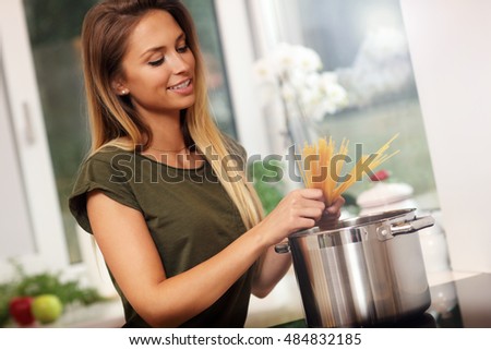 Picture of young woman preparing spaghetti in kitchen