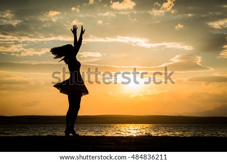 Successful woman jumping, dancing and having fun on sunset in beach. Freedom and happiness concept. Girl celebrating work out success.