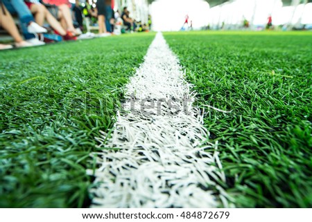 Closeup line on green soccer football field with player. Focus on the middle of the photo