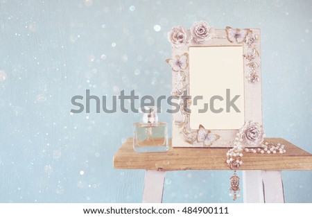 Blank victorian style frame, perfume bottle and necklace on wooden table. Ready to photograph montage