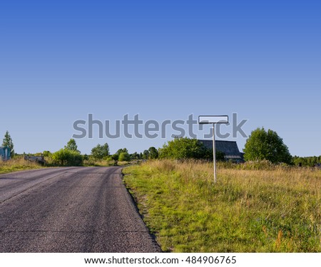 Road sign on a background of field and village houses.