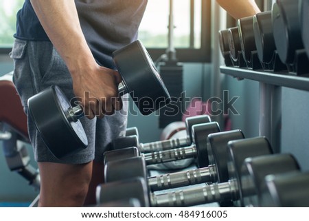 Hand holding dumbbell in the gym bodybuilding.