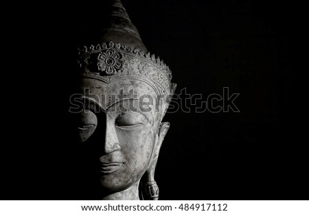 Spiritual Enlightenment. Traditional Thai buddha head with serene face and peaceful expression. High contrast modern lifestyle zen buddhism image on black background. Calm mind in mindful meditation.