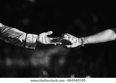 Black and white picture of hands touching with fingers over the grass