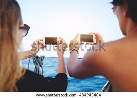 Back view of a couple are shooting video of beautiful sea view on their cell telephones with blank copy space screen for your advertising text message or promotional content during boating in yacht