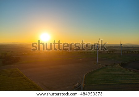 Beautiful sunset above the windmills on the field