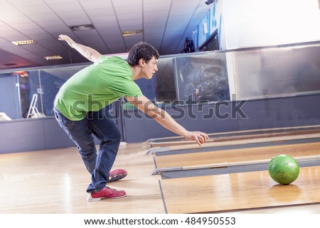 young boy pulls the ball on the bowling alley